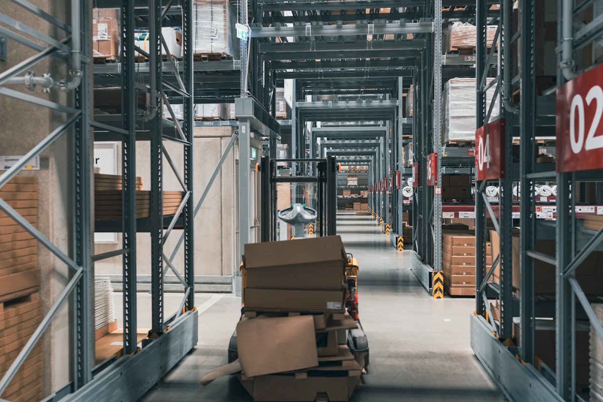 Cart of collapsed and set-aside cardboard boxes parked in a numbered warehouse racking aisle