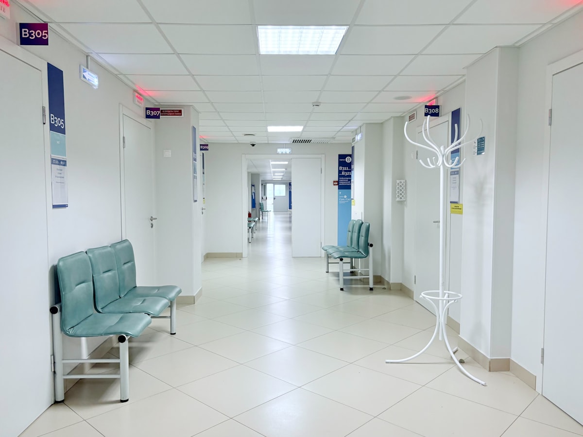Bright, quiet hospital outpatient corridor with an empty waiting-area seating bench