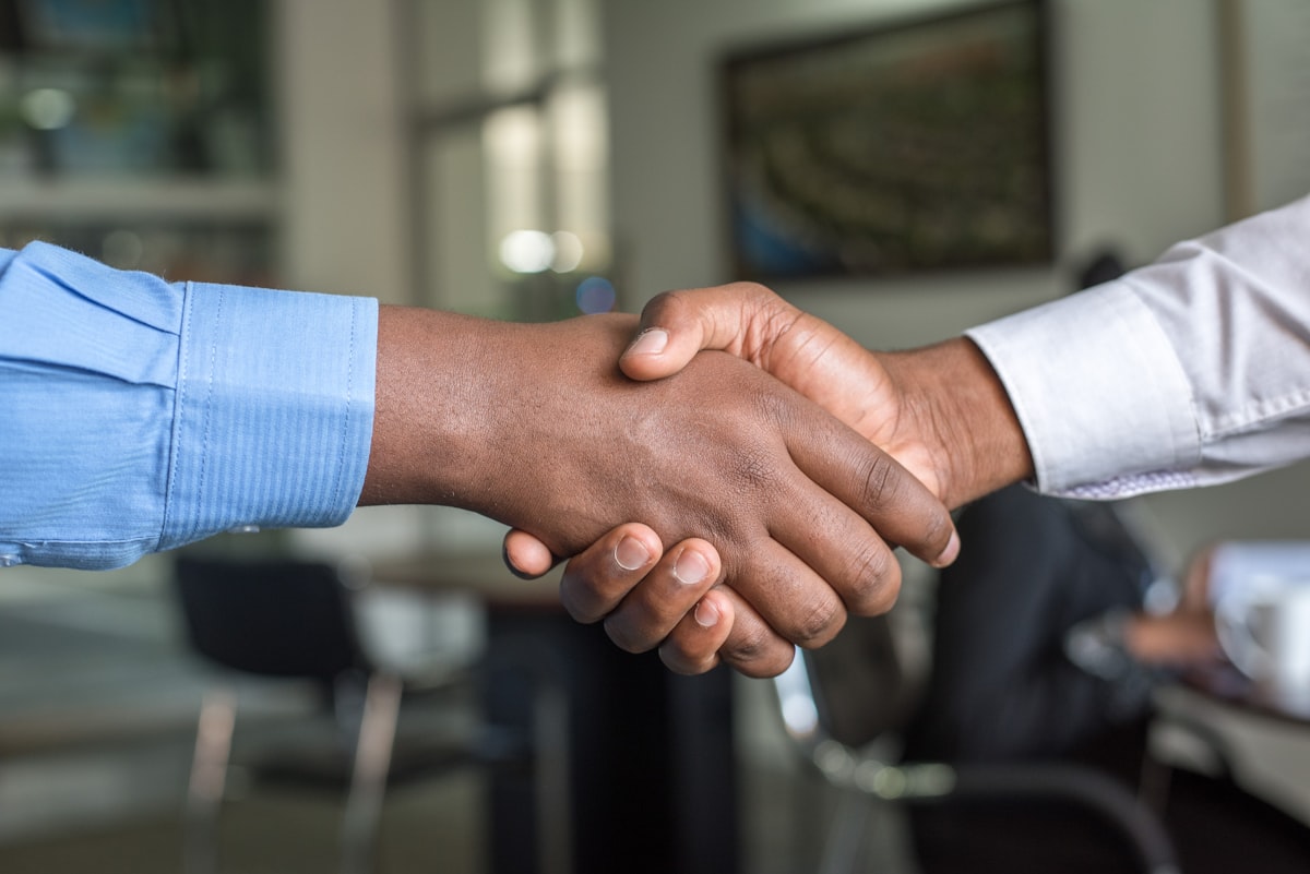 Two business professionals shaking hands over a deal in a bright office meeting room