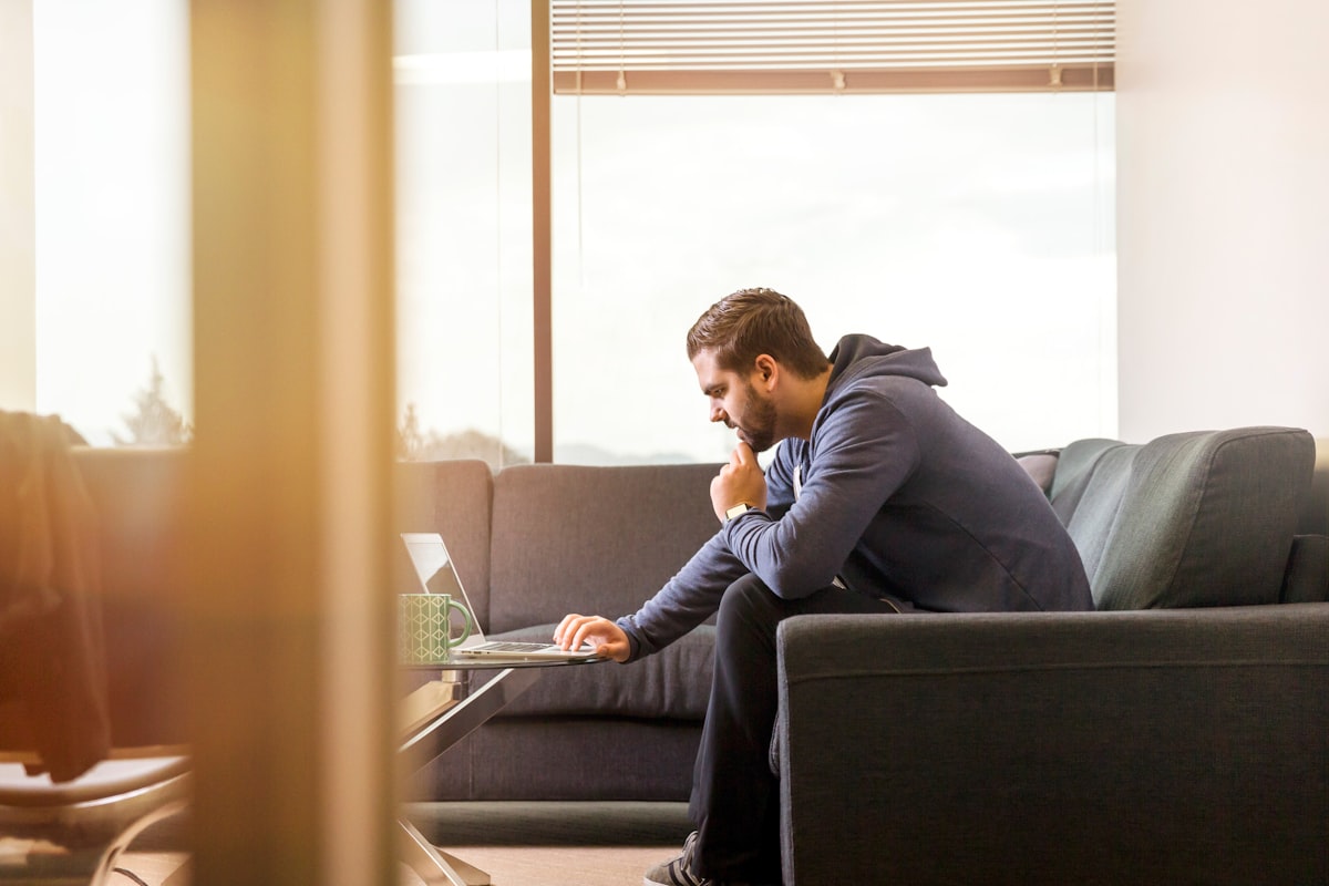 A manager focused on a laptop while seated in a bright, modern office lounge