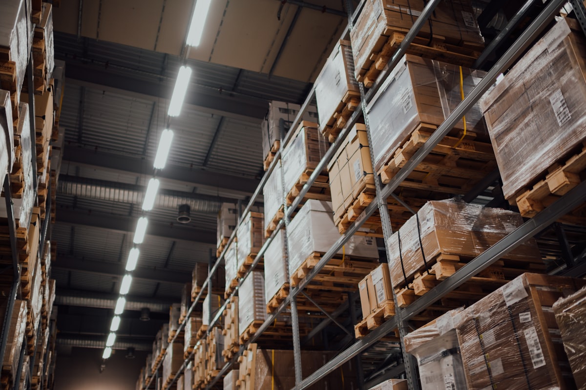 High warehouse aisle with steel racks stacked full of palletized cardboard inventory boxes